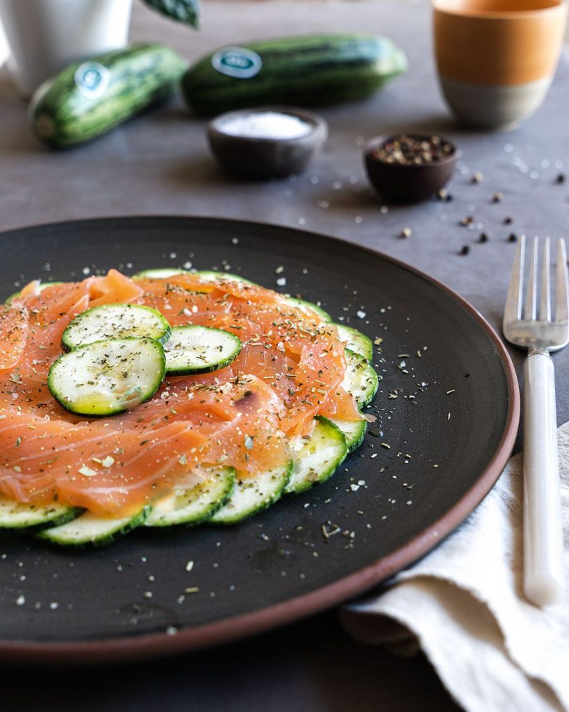 Un plat de carpaccio de salmó i carbassa crua, amb la carbassa tallada en rodanxes fines i el salmó fumat a sobre. Adornat amb oli d'oliva, herbes aromà tiques, sal i pebre. Una recepta rà pida i elegant que et farà semblar un cuiner.