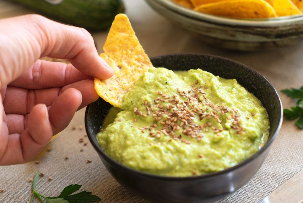 Un paté de carbassa crua que sembla un guacamole, pel seu color verd i perquè està presentat en un bol petit, fosc i rodo, amb un Dorito agafant una mica. Té unes llavors a sobre com a decoració. Verda, com t'estimo verda, i si és guacamole de carbassa crua, encara més! Anota aquesta recepta fitness!