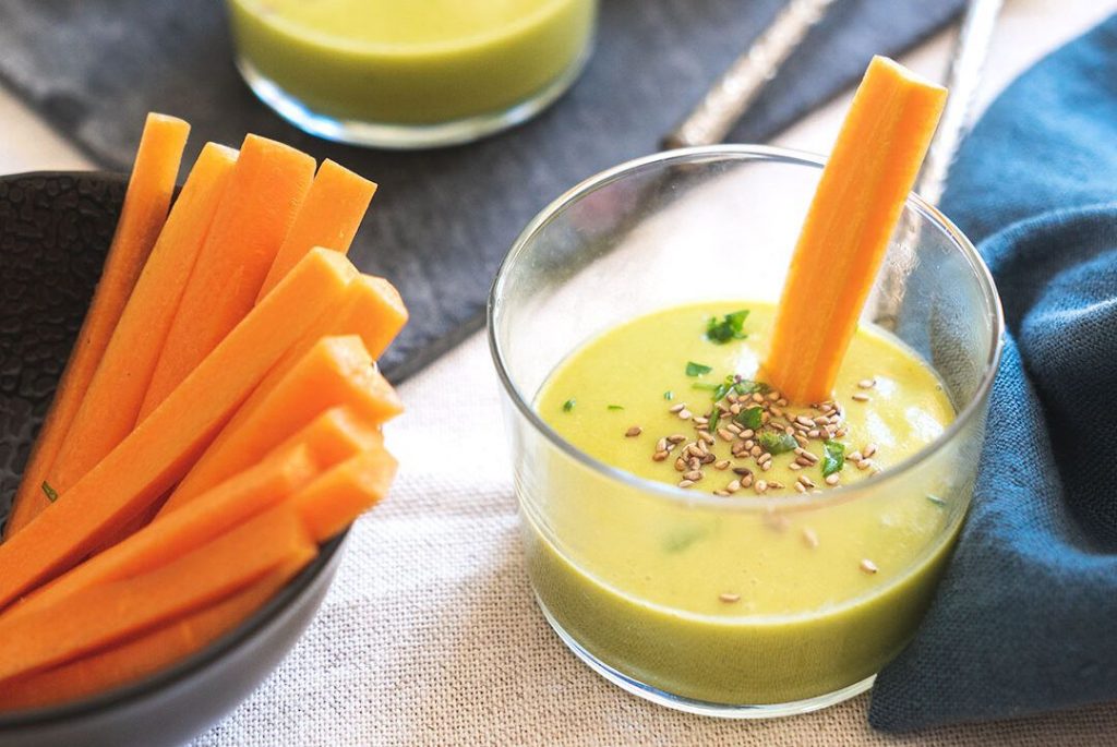 Descripción alternativa: Imagen de la receta "Vasitos de Crema", que muestra pequeños vasos elegantes llenos de una crema suave hecha de calabacines Crü, puerro, patata, zanahorias, caldo de verduras, nata para cocinar de avena, aceite de oliva virgen extra, sal, pimienta y nuez moscada. Cada vaso está adornado con una rodaja de zanahoria a modo de snack. Esta receta, presentada de manera atractiva y apetitosa, es perfecta para aquellos que extrañan la crema casera de su abuela.